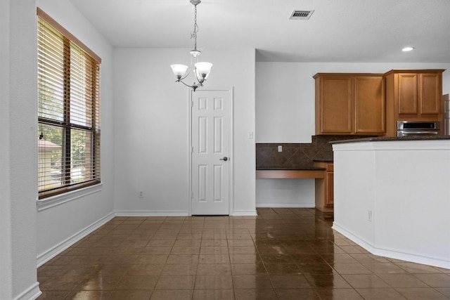 605 Whistlers Walk Trl, Cedar Park, TX 78613 - kitchen featuring dark countertops, a chandelier, dark tile patterned flooring, brown cabinets, and decorative backsplash