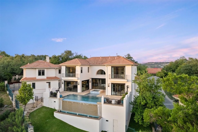 1508 Mesa Ridge Ln, Austin, TX 78735 - back of property at dusk featuring a balcony, stucco siding, a patio area, a fenced backyard, and a chimney
