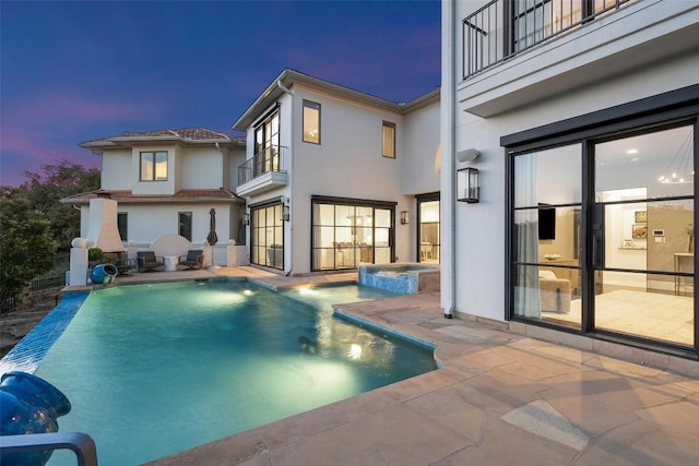 1508 Mesa Ridge Ln, Austin, TX 78735 - back of property at dusk featuring a balcony, stucco siding, a patio area, and a pool with connected hot tub