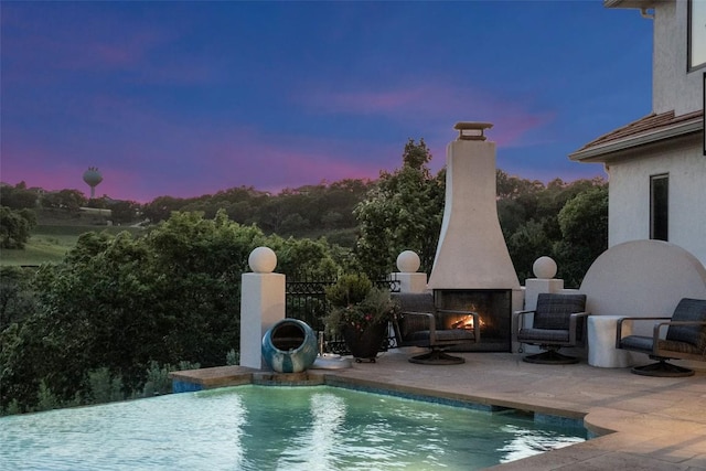 1508 Mesa Ridge Ln, Austin, TX 78735 - pool at dusk featuring a warm lit fireplace, a patio area, and an outdoor pool
