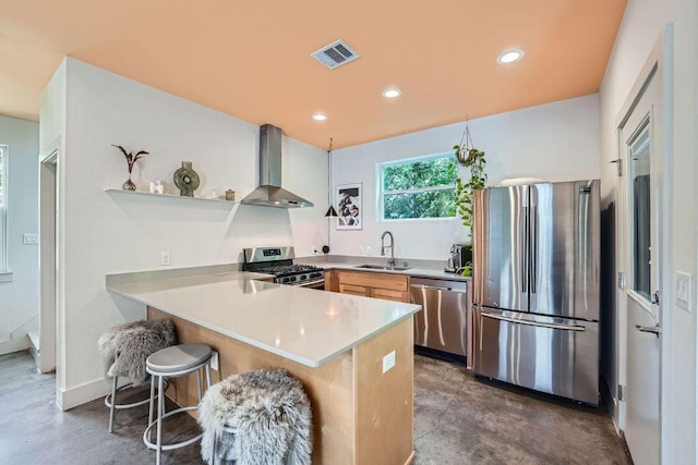 7311 Providence Ave Unit B, Austin, TX 78752 - kitchen featuring wall chimney exhaust hood, appliances with stainless steel finishes, a peninsula, a kitchen breakfast bar, and light countertops