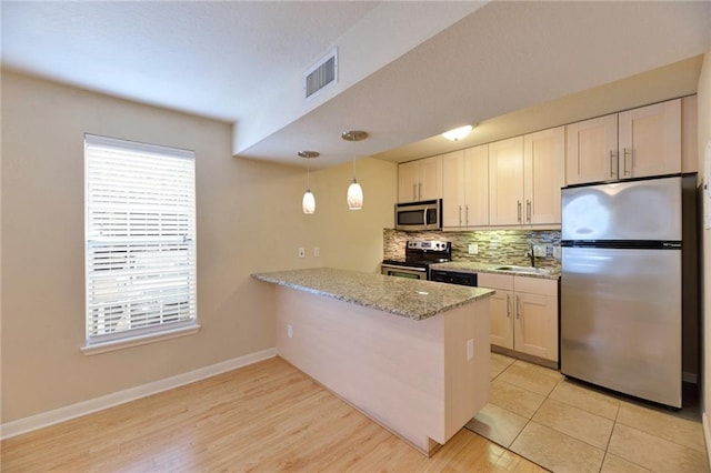 7685 Northcross Dr Unit 605, Austin, TX 78757 - kitchen featuring appliances with stainless steel finishes, backsplash, a peninsula, light stone counters, and pendant lighting