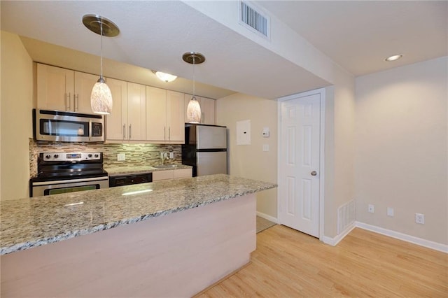 7685 Northcross Dr Unit 605, Austin, TX 78757 - kitchen featuring appliances with stainless steel finishes, light wood-type flooring, decorative backsplash, decorative light fixtures, and light stone counters