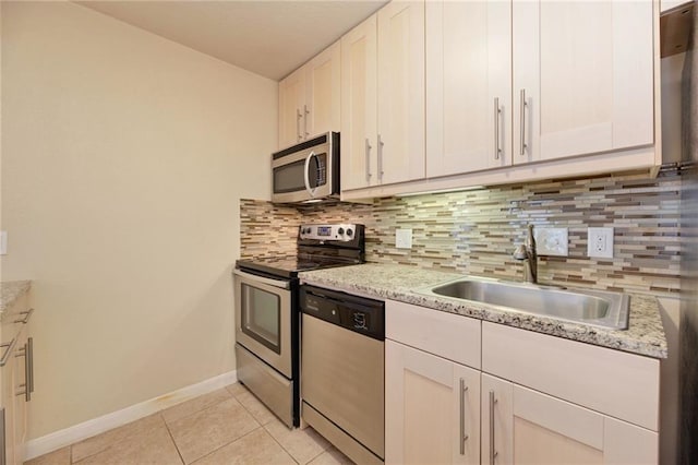 7685 Northcross Dr Unit 605, Austin, TX 78757 - kitchen with stainless steel appliances, backsplash, light tile patterned floors, and white cabinets
