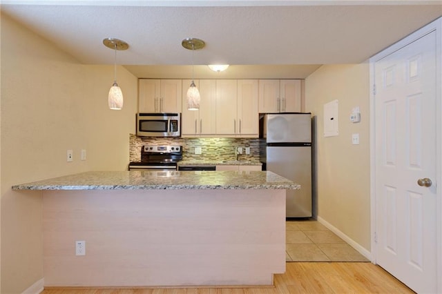 7685 Northcross Dr Unit 605, Austin, TX 78757 - kitchen featuring stainless steel appliances, backsplash, a peninsula, light stone counters, and hanging light fixtures