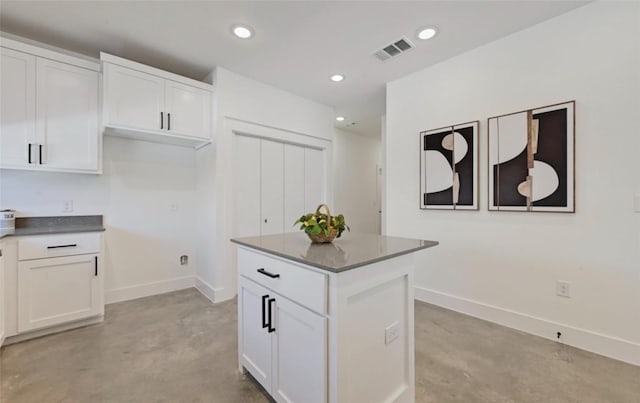 7306 Carver Ave Unit 1, Austin, TX 78752 - kitchen with concrete floors, white cabinetry, a kitchen island, recessed lighting, and dark countertops
