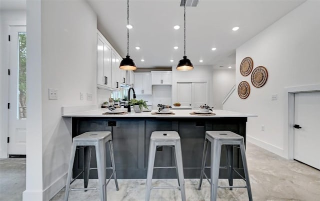 7613 Providence Ave Unit 1, Austin, TX 78752 - kitchen with a peninsula, white cabinets, light countertops, a kitchen breakfast bar, and recessed lighting