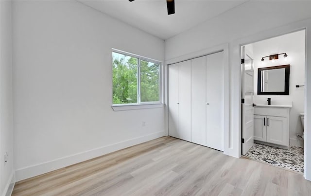 7613 Providence Ave Unit 1, Austin, TX 78752 - unfurnished bedroom featuring light wood-style flooring, a closet, ensuite bathroom, and a ceiling fan