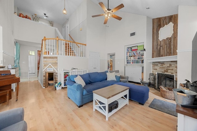1306 River Oak Dr, Leander, TX 78641 - living room with a stone fireplace, high vaulted ceiling, a ceiling fan, light wood finished floors, and stairs