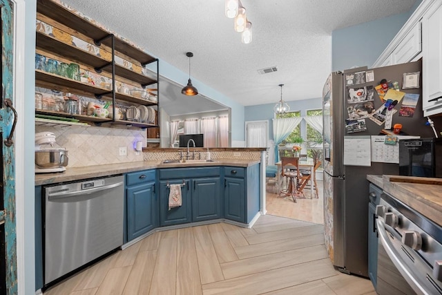 1306 River Oak Dr, Leander, TX 78641 - kitchen featuring stainless steel appliances, blue cabinets, a textured ceiling, a peninsula, and tasteful backsplash