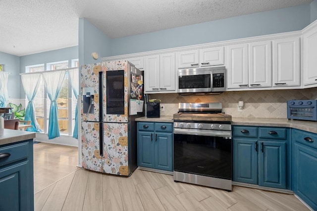 1306 River Oak Dr, Leander, TX 78641 - kitchen featuring stainless steel appliances, blue cabinets, backsplash, white cabinets, and a textured ceiling