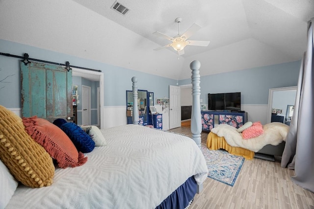 1306 River Oak Dr, Leander, TX 78641 - bedroom with vaulted ceiling, light wood-style flooring, ceiling fan, and a barn door