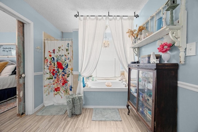 1306 River Oak Dr, Leander, TX 78641 - bathroom featuring a textured ceiling, a bath, wood finished floors, a shower with curtain, and ensuite bath