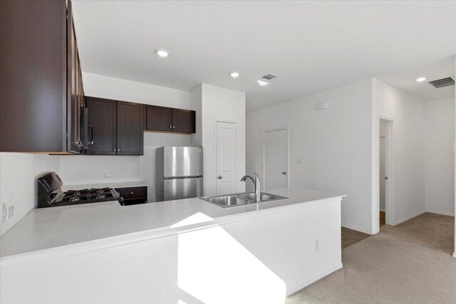 14320 Tordillo Dr, Elgin, TX 78621 - kitchen with freestanding refrigerator, gas stove, a peninsula, dark brown cabinetry, and light countertops