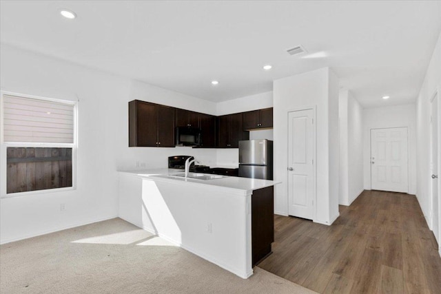 14320 Tordillo Dr, Elgin, TX 78621 - kitchen featuring black microwave, freestanding refrigerator, dark brown cabinetry, light countertops, and recessed lighting