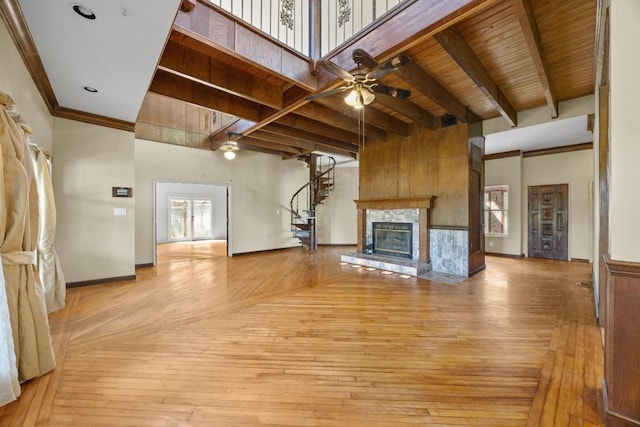 1001 S Gabriel Dr, Leander, TX 78641 - unfurnished living room with a ceiling fan, a glass covered fireplace, beam ceiling, light wood finished floors, and stairs