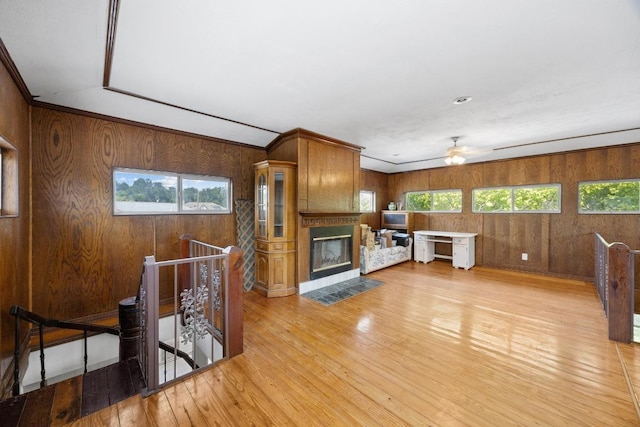 1001 S Gabriel Dr, Leander, TX 78641 - unfurnished living room with light wood-style floors, healthy amount of natural light, a ceiling fan, wood walls, and a fireplace with flush hearth