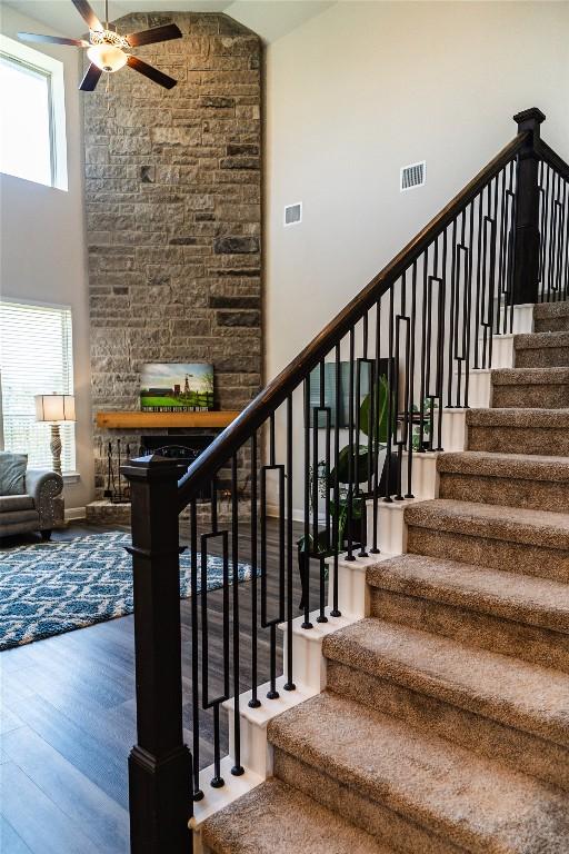 2616 Pine Branch Rd, Leander, TX 78641 - stairs with a ceiling fan, wood finished floors, a fireplace, and a high ceiling