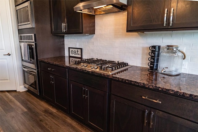 2616 Pine Branch Rd, Leander, TX 78641 - kitchen featuring wall chimney exhaust hood, stainless steel appliances, dark wood-style flooring, and dark stone countertops