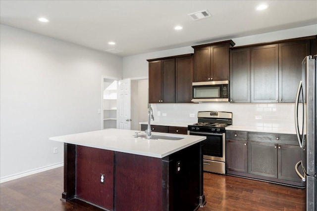 1629 W Broade St, Leander, TX 78641 - kitchen featuring appliances with stainless steel finishes, dark wood-style flooring, tasteful backsplash, an island with sink, and recessed lighting
