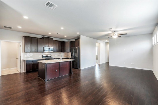1629 W Broade St, Leander, TX 78641 - kitchen with appliances with stainless steel finishes, open floor plan, a ceiling fan, light countertops, and dark brown cabinetry