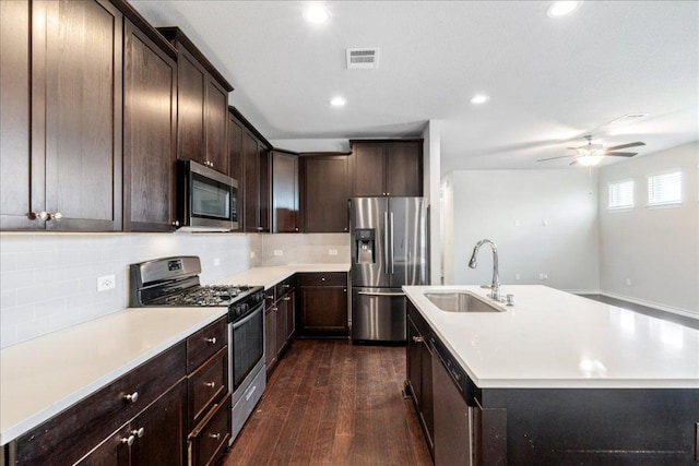 1629 W Broade St, Leander, TX 78641 - kitchen with stainless steel appliances, decorative backsplash, dark wood-style flooring, dark brown cabinetry, and an island with sink