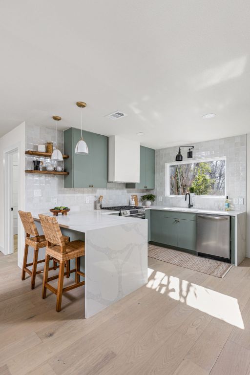 2105 Brunswick, Austin, TX 78723 - kitchen with stainless steel appliances, green cabinets, light wood-style floors, and a peninsula