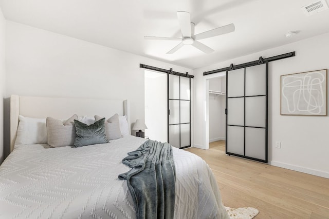 2105 Brunswick, Austin, TX 78723 - bedroom with a barn door, light wood-style floors, a ceiling fan, and a walk in closet