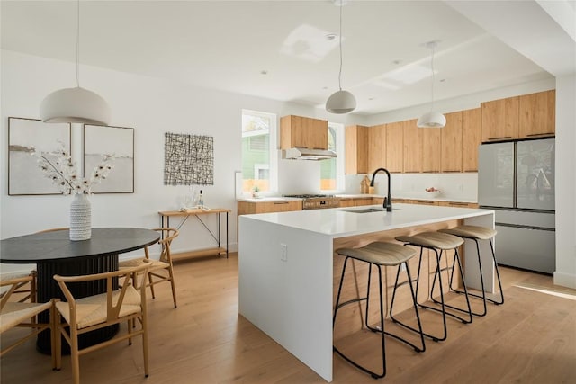 7516 Northcrest Blvd Unit 1, Austin, TX 78752 - kitchen featuring freestanding refrigerator, under cabinet range hood, light countertops, a center island with sink, and modern cabinets
