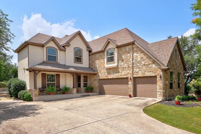 106 Tonkawa Trl W, Austin, TX 78738 - view of front facade with stucco siding, stone siding, concrete driveway, a garage, and covered porch