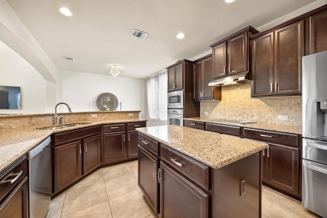 106 Tonkawa Trl W, Austin, TX 78738 - kitchen with stainless steel appliances, under cabinet range hood, a kitchen island, backsplash, and light tile patterned flooring