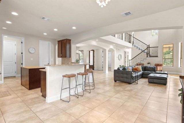 106 Tonkawa Trl W, Austin, TX 78738 - kitchen with arched walkways, light tile patterned floors, recessed lighting, a breakfast bar, and light stone counters