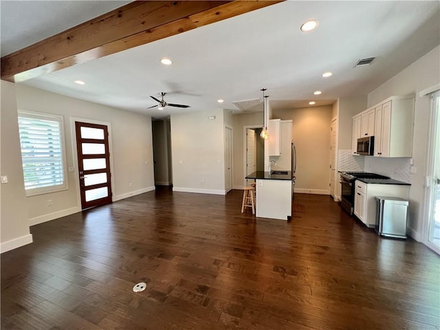 1126 Linden St Unit 2, Austin, TX 78702 - kitchen with black range with gas cooktop, stainless steel microwave, dark countertops, a breakfast bar, and white cabinets
