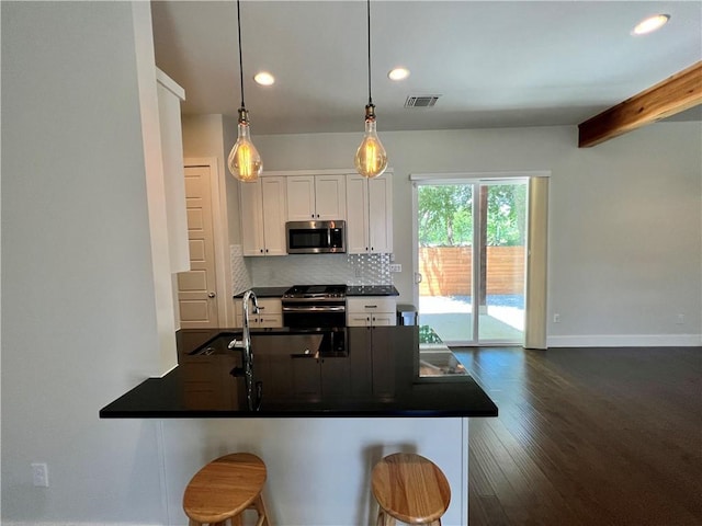 1126 Linden St Unit 2, Austin, TX 78702 - kitchen with dark countertops, stainless steel appliances, white cabinets, recessed lighting, and decorative backsplash