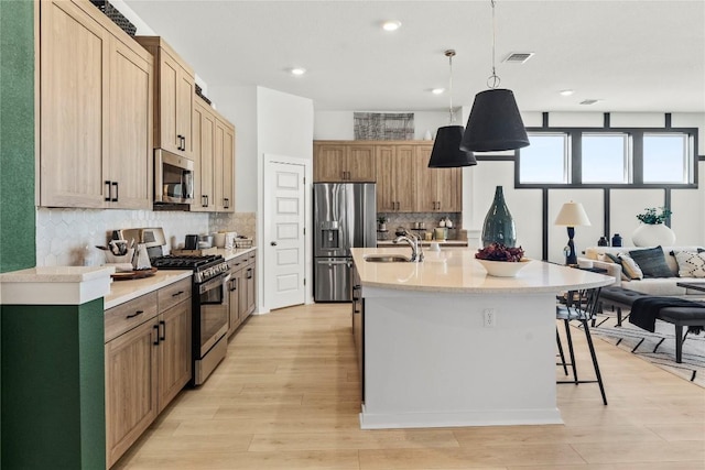 19512 Erna Dr, Pflugerville, TX 78660 - kitchen with stainless steel appliances, light wood-type flooring, tasteful backsplash, light countertops, and a kitchen bar