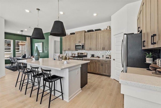 19512 Erna Dr, Pflugerville, TX 78660 - kitchen with stainless steel appliances, tasteful backsplash, a kitchen breakfast bar, light wood-style flooring, and recessed lighting