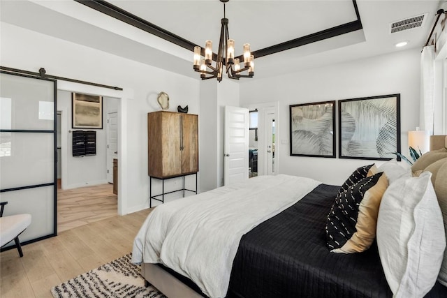 19512 Erna Dr, Pflugerville, TX 78660 - bedroom with light wood-type flooring, a chandelier, a barn door, a raised ceiling, and recessed lighting