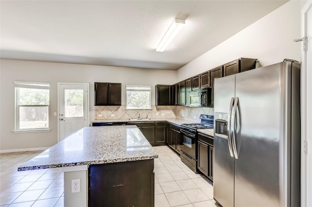 1710 Atlantica St, Cedar Park, TX 78613 - kitchen featuring black appliances, a kitchen island, decorative backsplash, light tile patterned flooring, and light stone counters