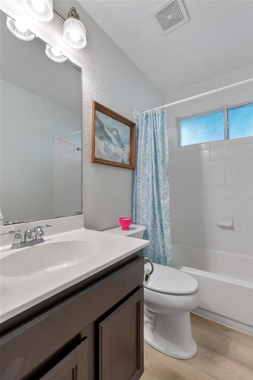 914 Flanagan Dr, Leander, TX 78641 - full bathroom with wood finished floors, vanity, shower / tub combo, and a textured wall