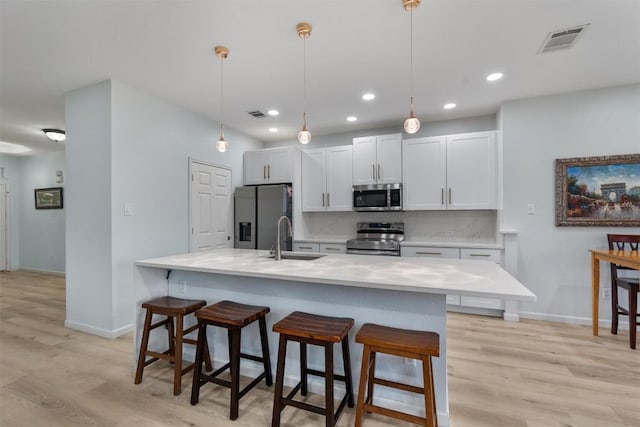 914 Flanagan Dr, Leander, TX 78641 - kitchen featuring appliances with stainless steel finishes, light wood-style flooring, an island with sink, a breakfast bar, and recessed lighting