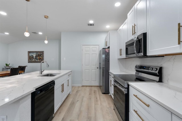 914 Flanagan Dr, Leander, TX 78641 - kitchen with stainless steel appliances, light wood-style flooring, decorative light fixtures, white cabinets, and recessed lighting