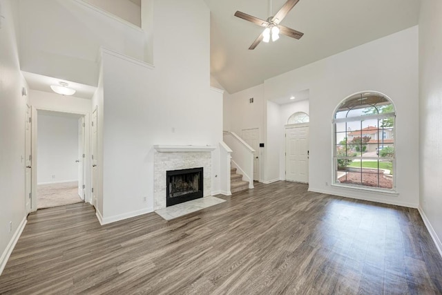 216 Cassandra Dr, Hutto, TX 78634 - unfurnished living room featuring high vaulted ceiling, wood finished floors, a ceiling fan, a stone fireplace, and stairs