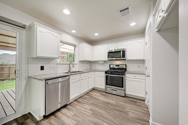 216 Cassandra Dr, Hutto, TX 78634 - kitchen with stainless steel appliances, light wood-type flooring, light stone countertops, white cabinets, and backsplash
