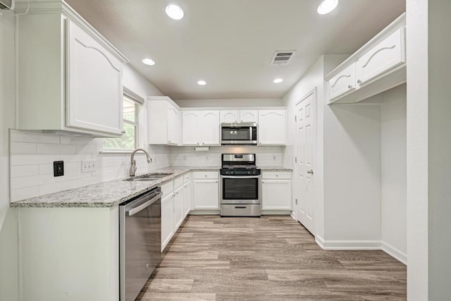 216 Cassandra Dr, Hutto, TX 78634 - kitchen featuring stainless steel appliances, light wood-style floors, light stone counters, tasteful backsplash, and recessed lighting