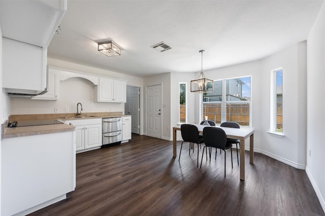 104 Live Oak Cir, Bertram, TX 78605 - kitchen with light countertops, a chandelier, white cabinets, stainless steel dishwasher, and dark wood-type flooring