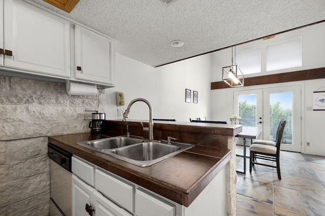 229 Comanche Ln, Point Venture, TX 78645 - kitchen featuring stainless steel dishwasher, dark countertops, white cabinetry, a textured ceiling, and a peninsula