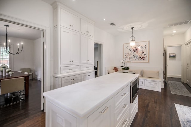 2908 Glenview Ave, Austin, TX 78703 - kitchen with a chandelier, dark wood-type flooring, white cabinets, stainless steel microwave, and decorative light fixtures