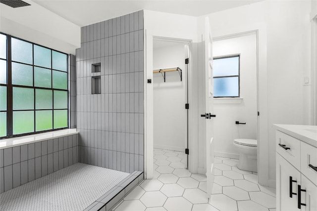 12416 Cassady Dr, Austin, TX 78727 - bathroom with healthy amount of natural light, tile patterned floors, tiled shower, and vanity