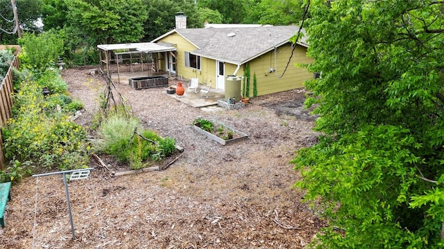 5201 Harvest Cir, Austin, TX 78745 - back of property with a garden, a shingled roof, a chimney, and a patio area