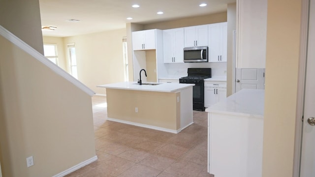 1024 Chad Loop, Round Rock, TX 78665 - kitchen with stainless steel microwave, black gas range, an island with sink, recessed lighting, and white cabinetry